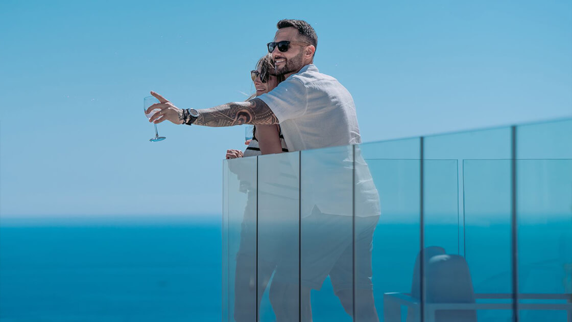 Couple profitant d’un verre sur un balcon avec vue panoramique sur la mer.