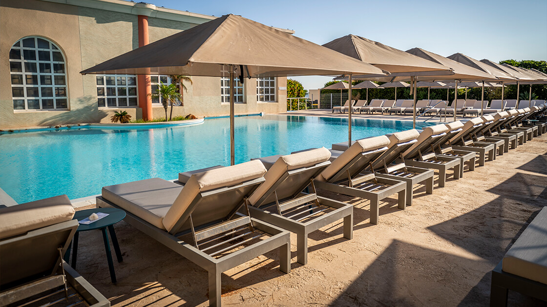 Piscine extérieure avec transats et parasols alignés.